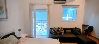 a bedroom with a couch and a balcony with a table at Cosy apartment close to the railway & metro stations in Athens