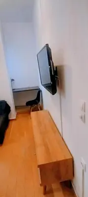 a room with a table and a tv on a wall at Cosy apartment close to the railway & metro stations in Athens