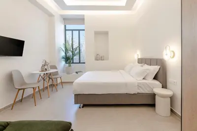 a white bedroom with a bed and a table at AthenianNest Asomaton Boutique Studio in Psyrri near Acropolis in Athens