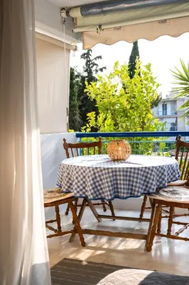 a table and two chairs on a porch with a table and a window at 15 minutes from Athens airport in Porto Rafti