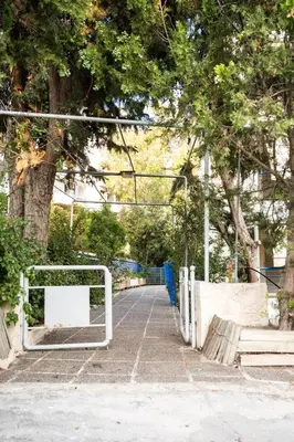 a sidewalk with a white gate and a tree at 15 minutes from Athens airport in Porto Rafti