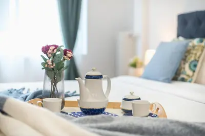 a table with a vase of flowers and cups on a bed at Elegant Dimitra, Your Beautiful Home in Athens, by Acropolin in Athens