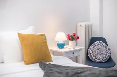 a bed with a chair and a table with a lamp at Elegant Dimitra, Your Beautiful Home in Athens, by Acropolin in Athens