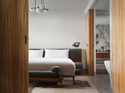 a bedroom with a bed and a chair at Conrad Athens The Ilisian in Athens