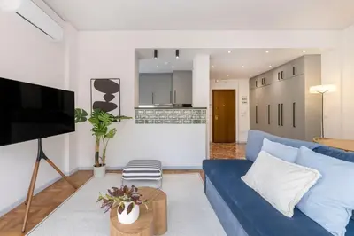 a living room with a blue couch and a kitchen at Calming 1BR Apartment with Acropolis view in Athens