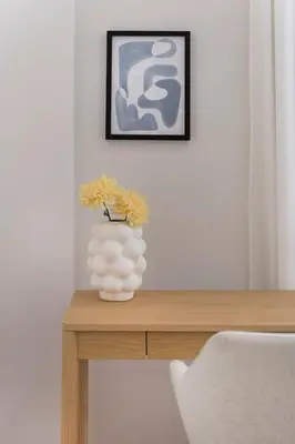 a white vase with yellow flowers on a wooden table at Calming 1BR Apartment with Acropolis view in Athens