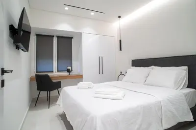 a white bedroom with a white bed and a chair at Filoxenia MG Projects-City Living Metro in Athens