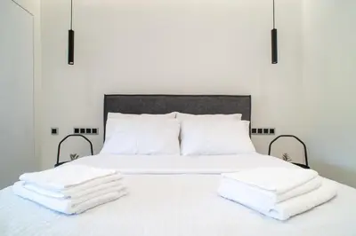a white bed with three towels on top of it at Filoxenia MG Projects-City Living Metro in Athens