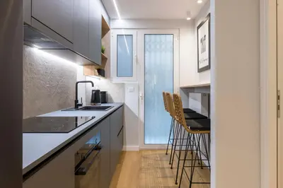 a kitchen with white cabinets and bar stools at Voukourestiou Grand Residence 56 in Athens