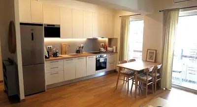 a kitchen with white cabinets and a table and a refrigerator at Dafne Athens renovated apartment 170m from Metro in Athens