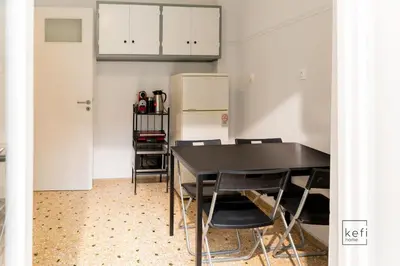 a kitchen with a black table and chairs and a refrigerator at Cozy 3-BDR Flat at Tavros Metro - 10 Min to Center in Athens