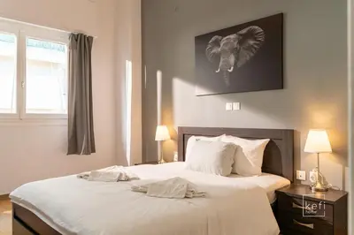 a bedroom with a bed with white sheets and an elephant picture at Cozy 3-BDR Flat at Tavros Metro - 10 Min to Center in Athens