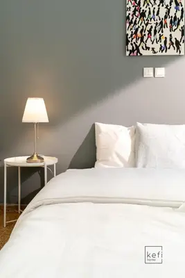 a bedroom with a white bed and a table with a lamp at Cozy 3-BDR Flat at Tavros Metro - 10 Min to Center in Athens