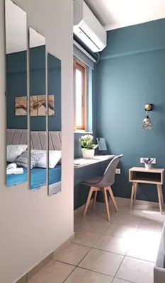 a bedroom with blue walls and a table and a desk at Piraeus Port Rooms in Piraeus