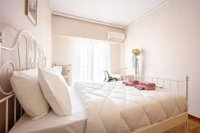 a white bedroom with a large bed with white pillows at Stylish 2BD with Balcony in Central Athens in Athens