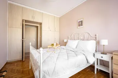 a white bedroom with a white bed and a table at Stylish 2BD with Balcony in Central Athens in Athens