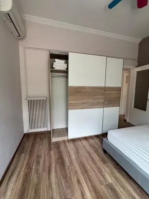 a bedroom with white walls and a bed and wooden floors at The Ioustinianou Residence in Athens