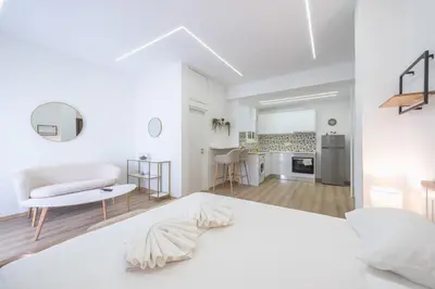 a white bedroom with a white bed and a kitchen at Ble Elia Monastiraki Suite in Athens