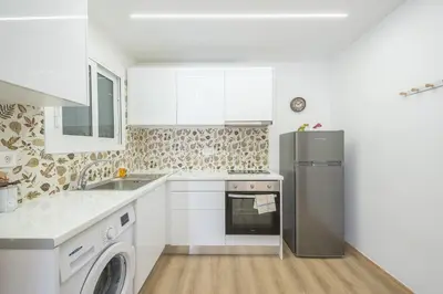 a white kitchen with a refrigerator and a dishwasher at Ble Elia Monastiraki Suite in Athens