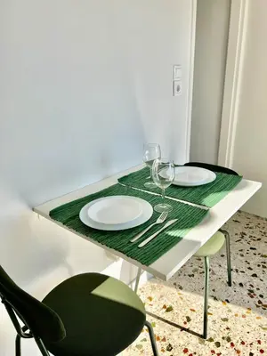 a green and white table with two plates and wine glasses at Athens sky & Acropolis view rooftop apartment! in Athens