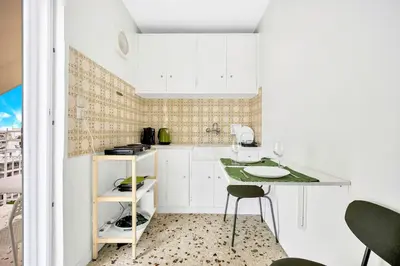 a kitchen with white cabinets and a table and chairs at Athens sky & Acropolis view rooftop apartment! in Athens