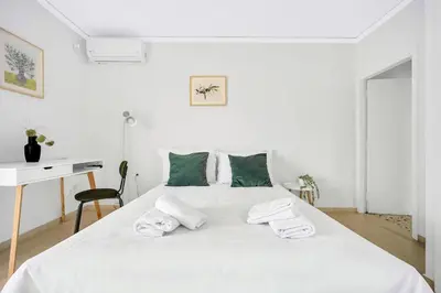 a white bedroom with a large white bed with green pillows at Athens sky & Acropolis view rooftop apartment! in Athens