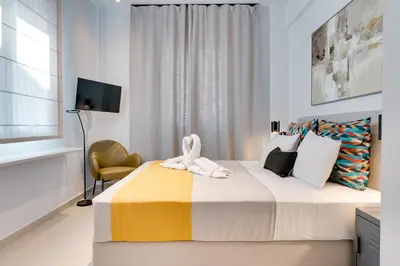 a bedroom with a large bed and a chair at Honey studio at Kypseli in Athens