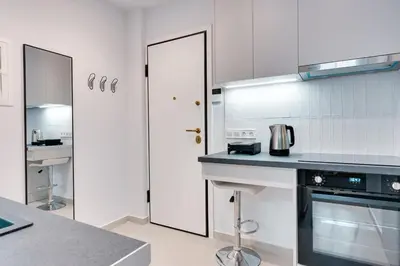 a white kitchen with a stove and a sink at Honey studio at Kypseli in Athens
