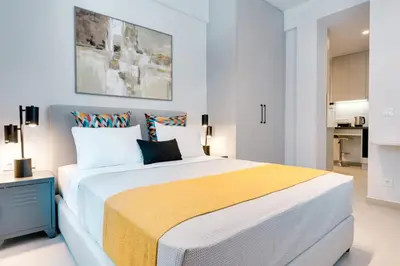 a white bedroom with a large bed with a yellow blanket at Honey studio at Kypseli in Athens