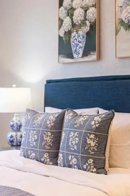 a bed with a blue and white pillow and a vase of flowers at Stylish 2BR-2BA condo in Glifada in Athens