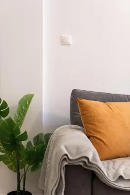 a couch with a yellow pillow and a plant at 1BR Modern & Cozy Apt Near Metro and Acropolis in Athens