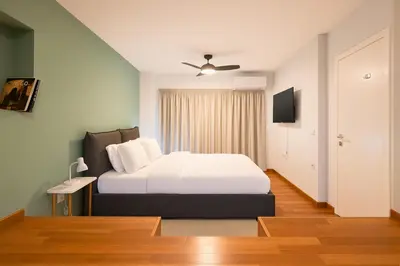 a bedroom with a white bed and a television at 2BR Luxurious Apt in Mets 20 min From Acropolis in Athens