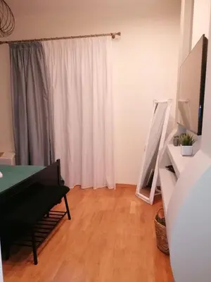 a living room with a white curtain and a wooden floor at SOKRATESg in Athens