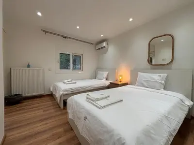 a bedroom with two beds with a mirror and a radiator at Cute Detached Home near Glyfada Center in Athens
