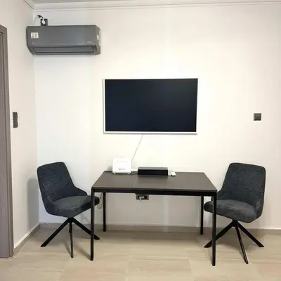 a desk with two chairs and a television on a wall at The Perch Kolonaki Square Studio Prime Location in Athens