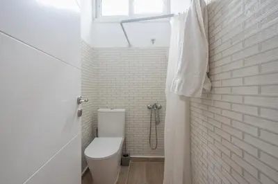 a white bathroom with a toilet and a shower at Cozy Loft Vouliagmeni in Athens