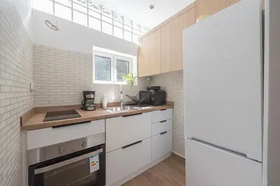 a kitchen with white cabinets and a sink at Cozy Loft Vouliagmeni in Athens