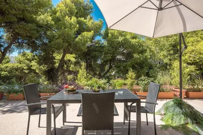a black table and chairs with an umbrella at Cozy Loft Vouliagmeni in Athens