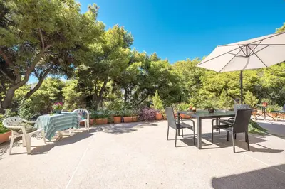 a patio with a table and chairs and an umbrella at Cozy Loft Vouliagmeni in Athens