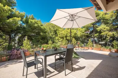 a table and chairs with an umbrella on a patio at Cozy Loft Vouliagmeni in Athens