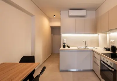 a kitchen with white cabinets and a wooden table at Elvita Apartments 5 in Athens