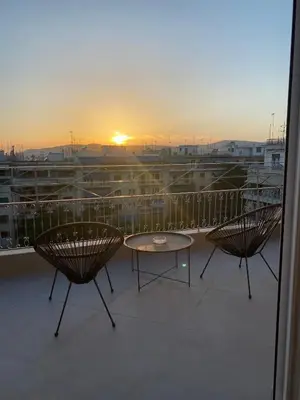 two chairs and a table on a balcony with the sunset at In the heart of Athens overlooking Kalligas Square! in Athens
