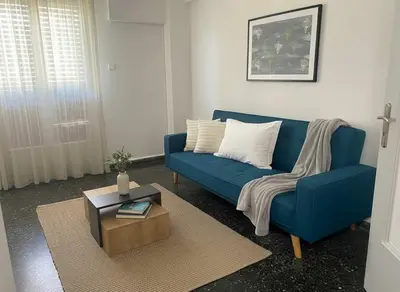 a blue couch in a living room with a table at Your Piraeus Escape Cozy One-Bedroom Apartment in Piraeus