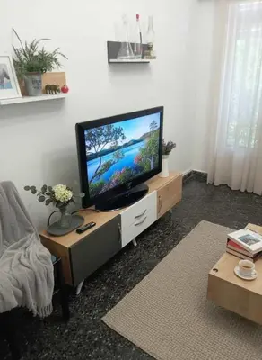 a living room with a flat screen tv on a stand at Your Piraeus Escape Cozy One-Bedroom Apartment in Piraeus