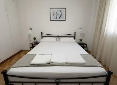 a bedroom with a large bed with white sheets at Your Piraeus Escape Cozy One-Bedroom Apartment in Piraeus