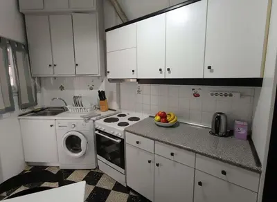 a kitchen with white cabinets and a washing machine at Your Piraeus Escape Cozy One-Bedroom Apartment in Piraeus