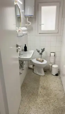 a bathroom with a toilet and a sink and a window at Athens Central Gem 2-Bedroom Retreat in Athens