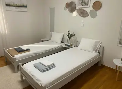 two beds in a room with white walls at Athens Central Gem 2-Bedroom Retreat in Athens