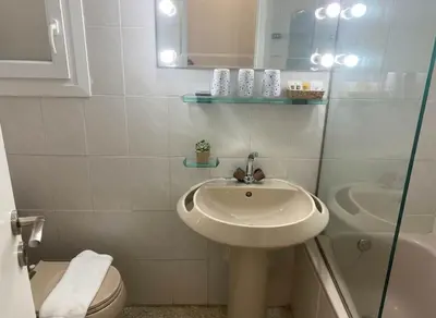 a white bathroom with a sink and a toilet at Athens Central Gem 2-Bedroom Retreat in Athens