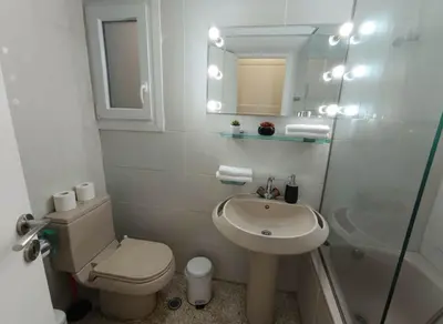 a bathroom with a sink and a toilet and a mirror at Athens Central Gem 2-Bedroom Retreat in Athens